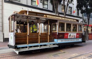 A brown streetcar on a red brick road, Powell and Mason Streets and San Francisco Municipal Railway written on the side.